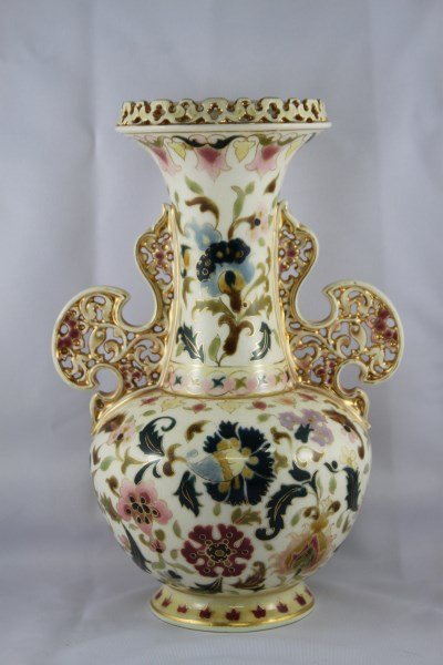 Zsolnay Twin Handled Porcelain Vase,: with a pierced shaped lip, above waisted neck with shaped pierced handles and baluster body, decorated with stylised flowers and foliage in tones of green, pink and brown, h 24cm