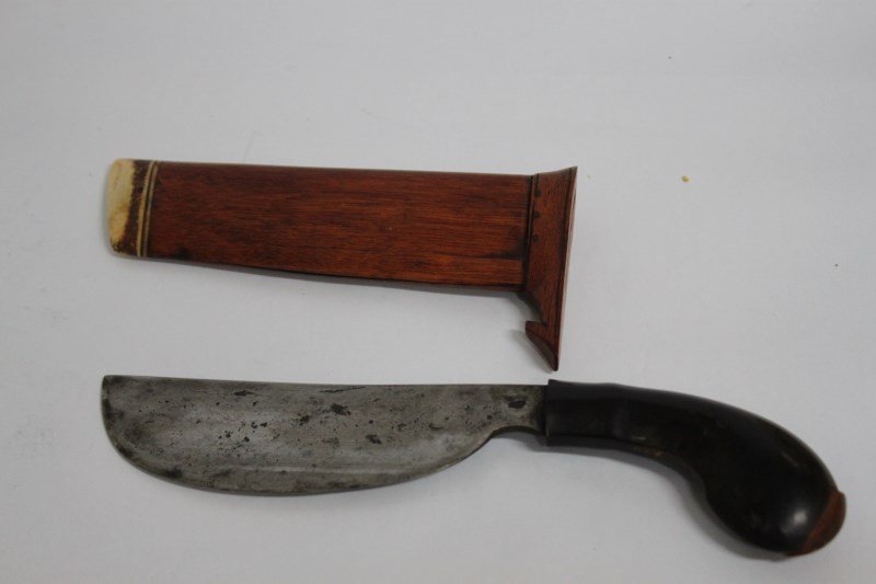 Javanese Bendo,: or small machete. Heavy half-moon shaped cutting blade, straight back, maker’s mark, plain horn hilt; sheath in light-coloured wood, fastened with pegs, with bone inlay at foot, used for cutting are