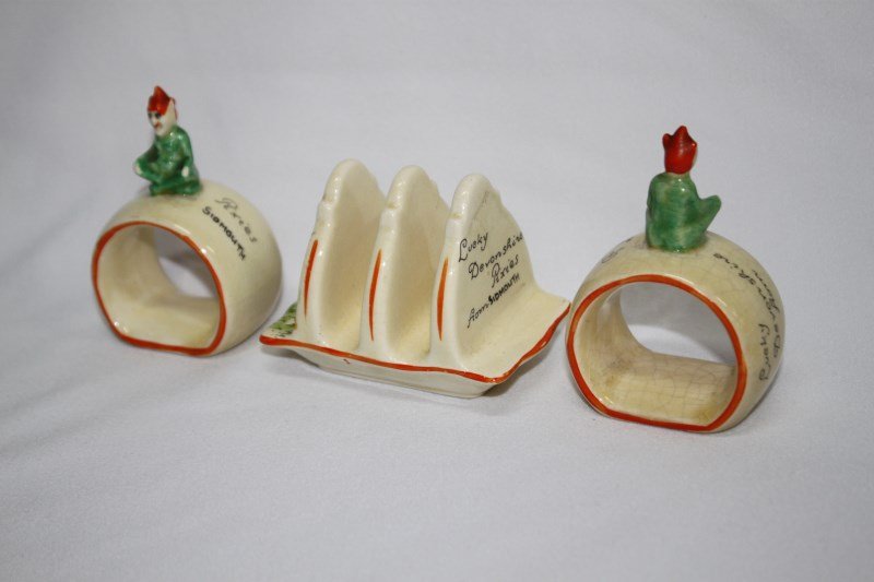 Two Crown Devon 'Lucky Pixies' Napkin Rings,: and a matching toast rack. (3)