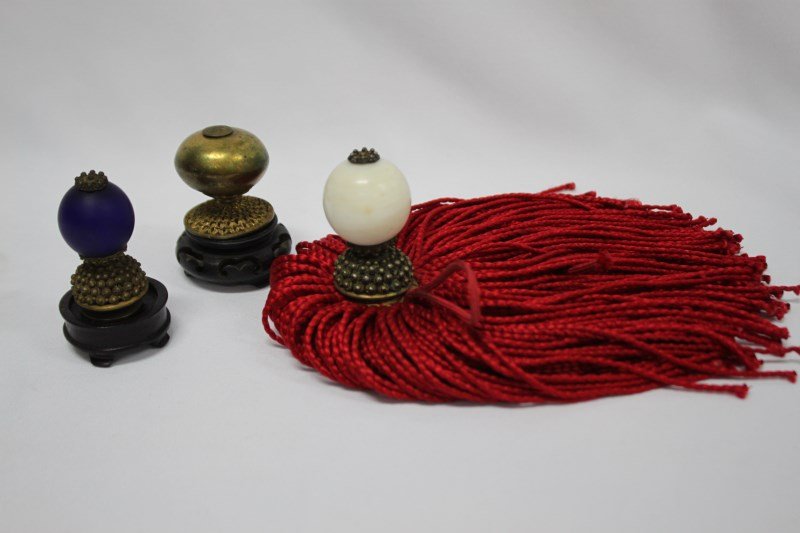 Three Chinese Hat Finials,: 4th rank finial (opaque blue); 6th rank finial (white) with the fringe from a winter hat; 7th rank finial (gilt copper), (3)