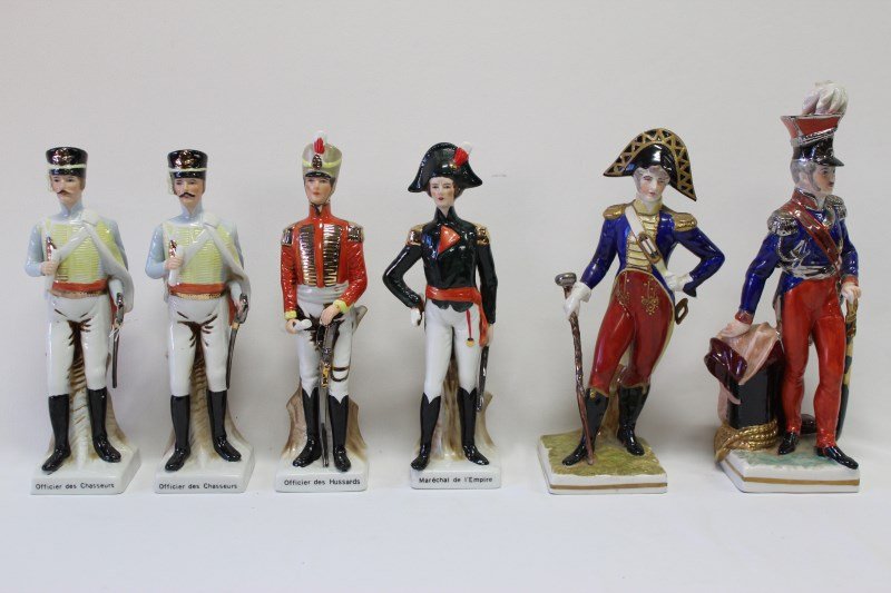 Six Porcelain Figures,: depicting Napoleonic officers, modelled on naturalist bases, two Capodimonte with underglaze blue factory marks, h 27cm, 24cm, a/f (6)