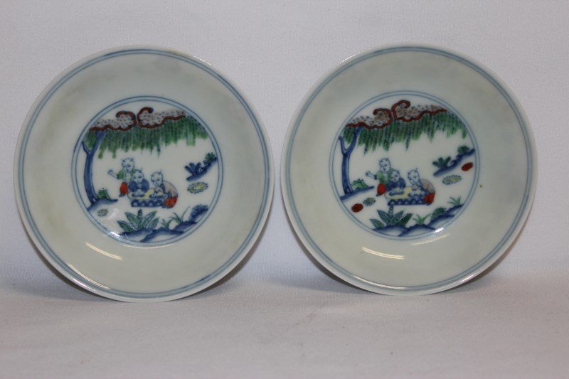 Pair of Chinese Doucai Porcelain Dishes,: with central roundels decorated with children seated under a tree, the exterior decorated with the Buddhist precious items, underglaze six character within double rings to base, d 12cm (2)