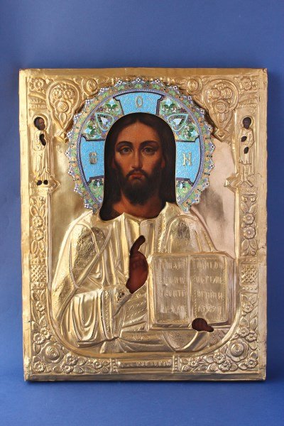The Russian Icon of Christ Pantocrator,: the saint portrayed traditionally with deep colours, the ormolu oklad chased with checkered pattern in to the background, the silver and cloisonne enamel halo decorated with foliate scrolls, the silve
