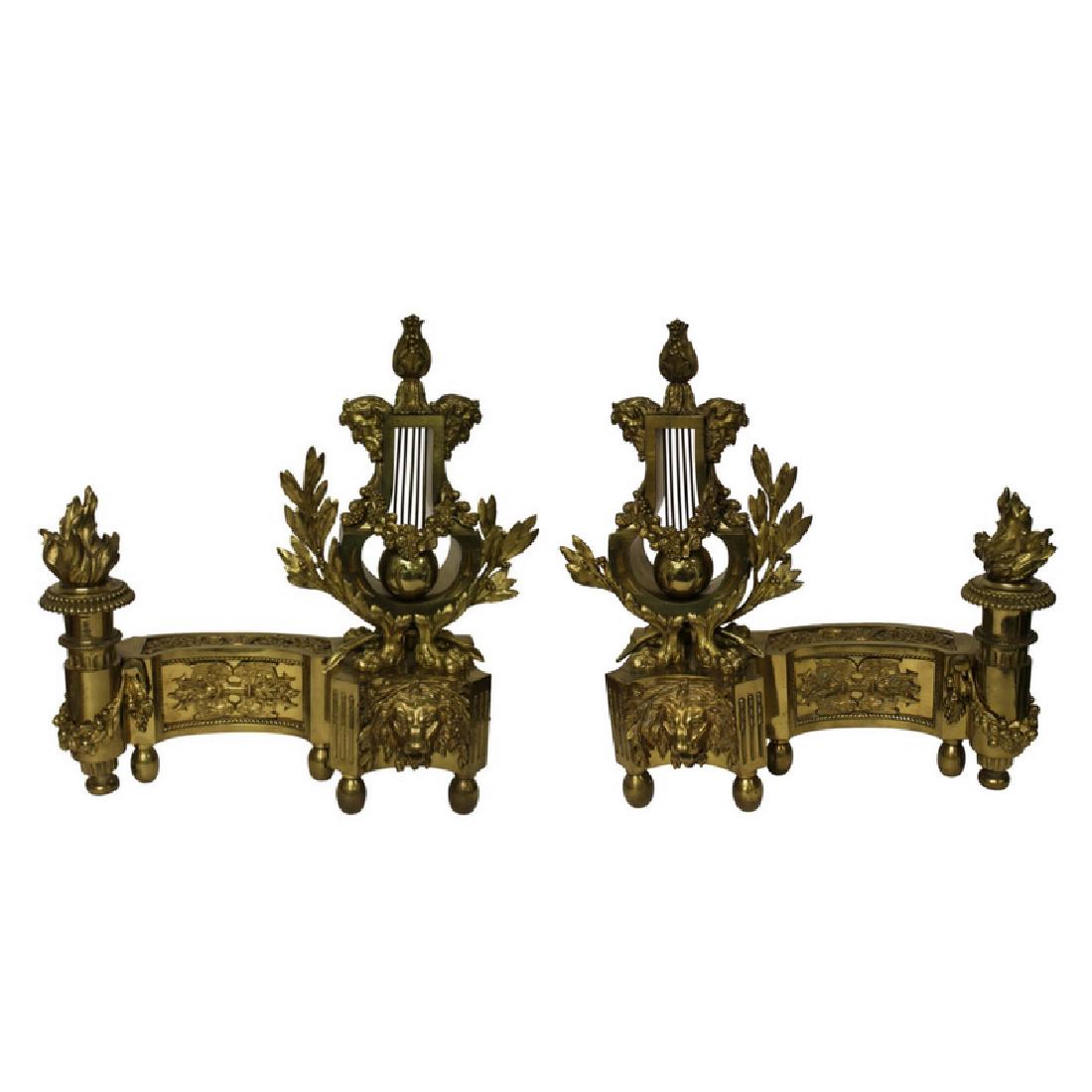 Quchtin-Claude Pitorn Louis XVI Style Chenets: Pair of chenets in the style of Louis XVI, Quchtin-Claude Pitorn. Gold in color. Circa 19th Century. Losses to the foliage tips on each chenet, otherwise good condition.