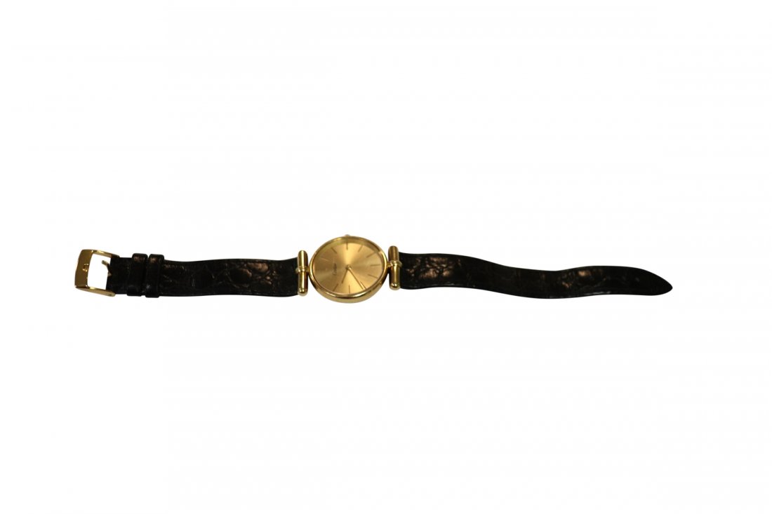 18K CARTIER LADIES WRISTWATCH: 18 Karat Gold Cartier wristwatch. Marked on the front Swiss Made and the inside back Baume & Mercier Geneve Swiss 750. Measuring 9 inches with the band; the watch face 1 inch in diameter. Watch clasp 