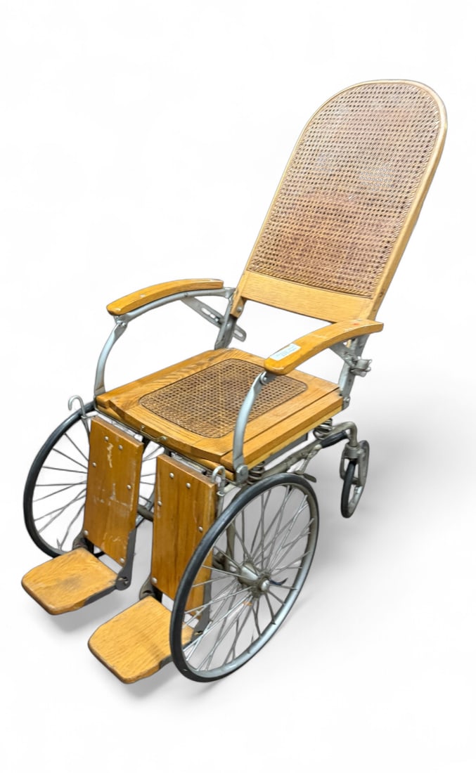 Antique Wheelchair: Antique wheelchair, characterized by its wooden frame, cane seat and back, and large spoked wheels.