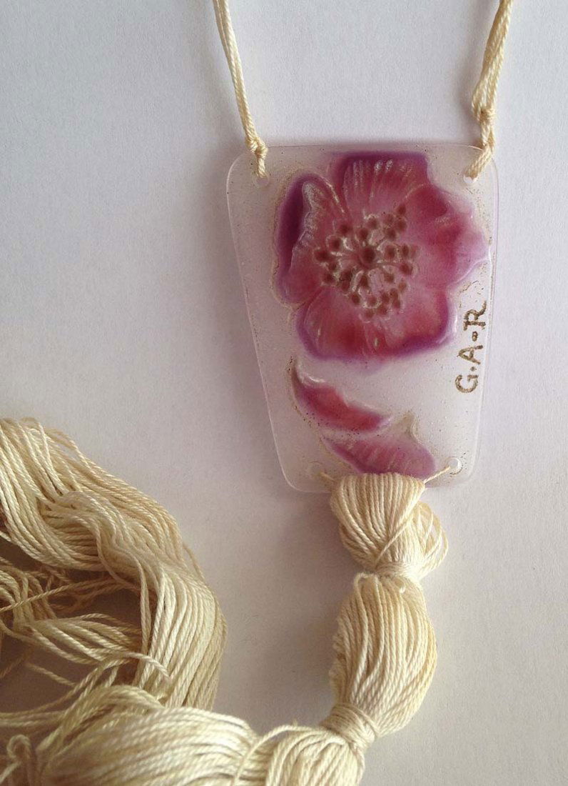 ARGY-ROUSSEAU Gabriel (1885-1953). Pendentif: ARGY-ROUSSEAU Gabriel (1885-1953) Pendentif rectangulaire a la fleur PÃ¢te de cristal dominante mauve clair, travaille en camee a tons violaces. Cordelette en tour de cou a pompon Signe dans la pÃ�