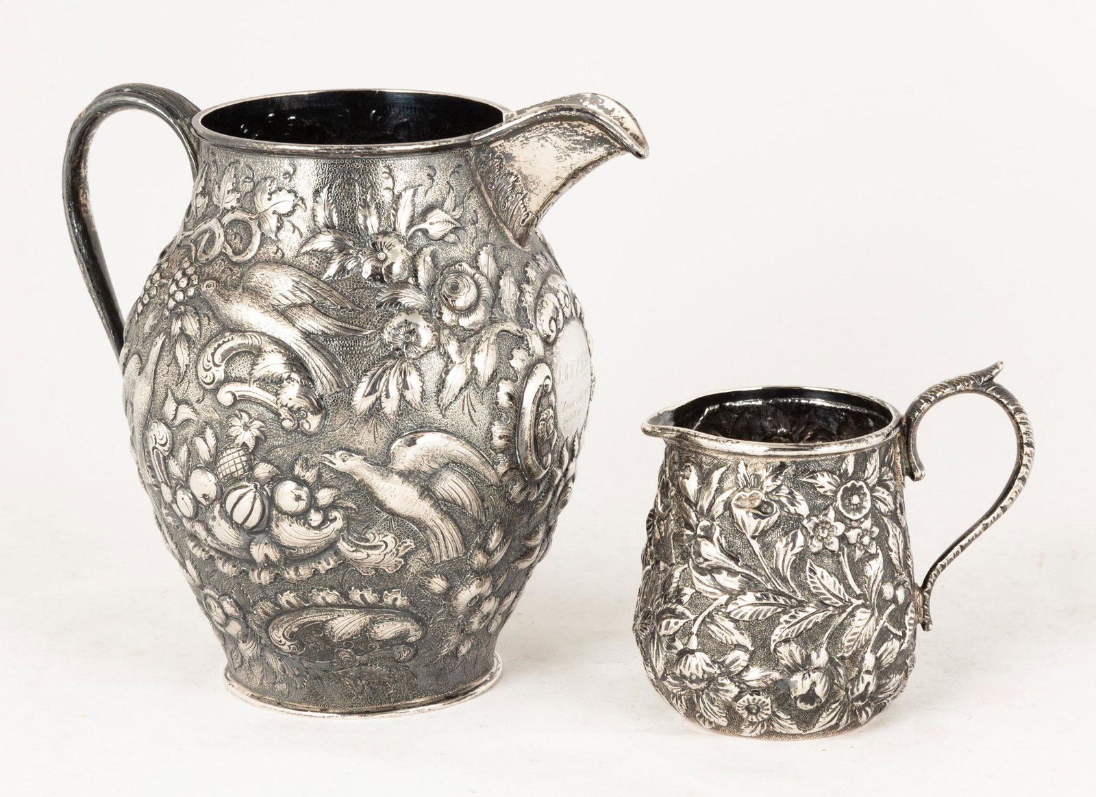 Two Sterling Repoussé Pitchers: One A.E. Warner. Smaller one, S. Kirk. Warner pitcher has engraved presentation. 15.6 ozt. Max Ht 6" The Estate of George Jamison, Corning, NY.