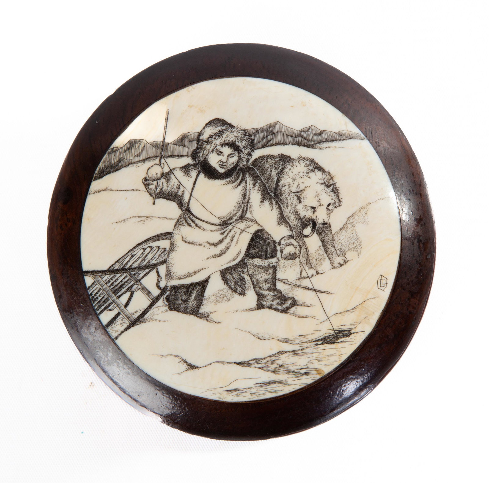 Engraved Eskimo Snuffbox: Engraved Eskimo Snuffbox Artist signed and engraved bone depicting an Eskimo and sled dog ice fishing, mounted on a carved walnut. Ht. 1 1/4 in. Dia. 3 3/8 in.