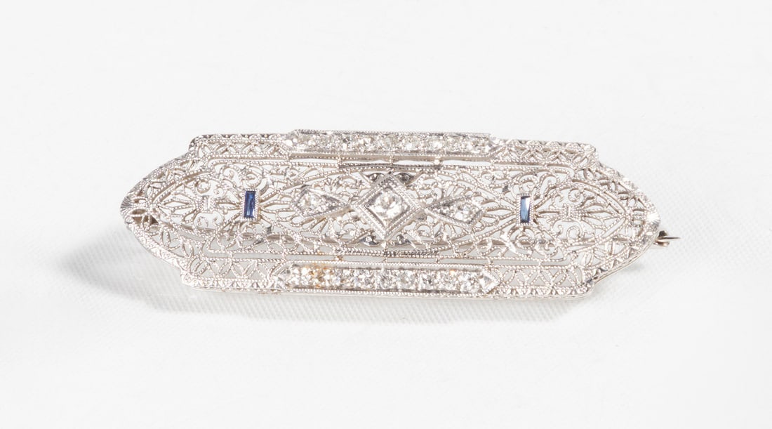 Art Deco "Antique Filagree" Bar Style Diamond Brooch: Art Deco "Antique Filagree" Bar Style Diamond Brooch 18K gold, platinum, diamond, and sapphire. Approximate total weight: .47 cts. VS clarity, G-H color. L. 2 in. Purchase Note: New customers purchasi