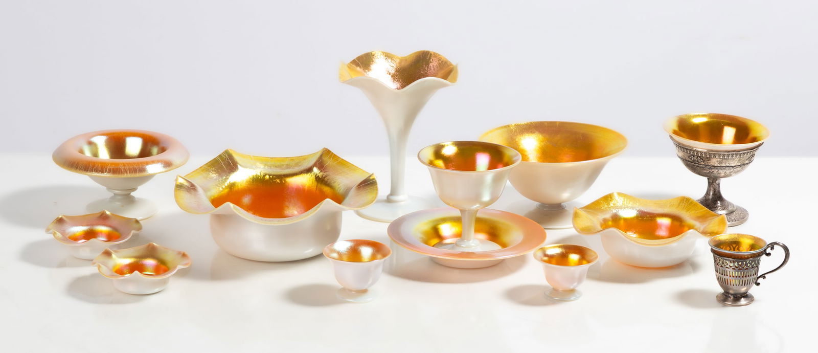 Steuben Gold Aurene & Calcite Tableware: Steuben Gold Aurene & Calcite Tableware Corning, New York, early 20th century. Blown glass. Gold aurene over calcite. Two have sterling silver mounts. Max Ht. 16 in. The collection of Bill Mehlenbache