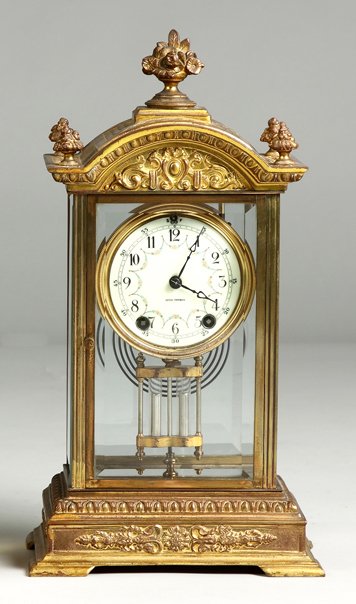 Seth Thomas Empire: Seth Thomas Empire . Relief cast brass case. Porcelain dial. Mercury style pendulum. 8 day time and strike brass movement. Ht. 15".
