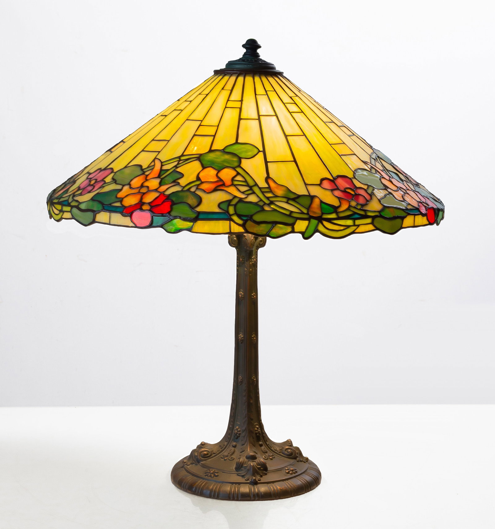 Attributed to Wilkinson Arts and Crafts Leaded Glass Floral Border Table Lamp: Attributed to Wilkinson Arts and Crafts Leaded Glass Floral Border Table Lamp American, early 20th century. Leaded glass, patinated bronze. Ht. 25 1/2 in. Shade 22 in. The collection of Dr. Bruce A. A