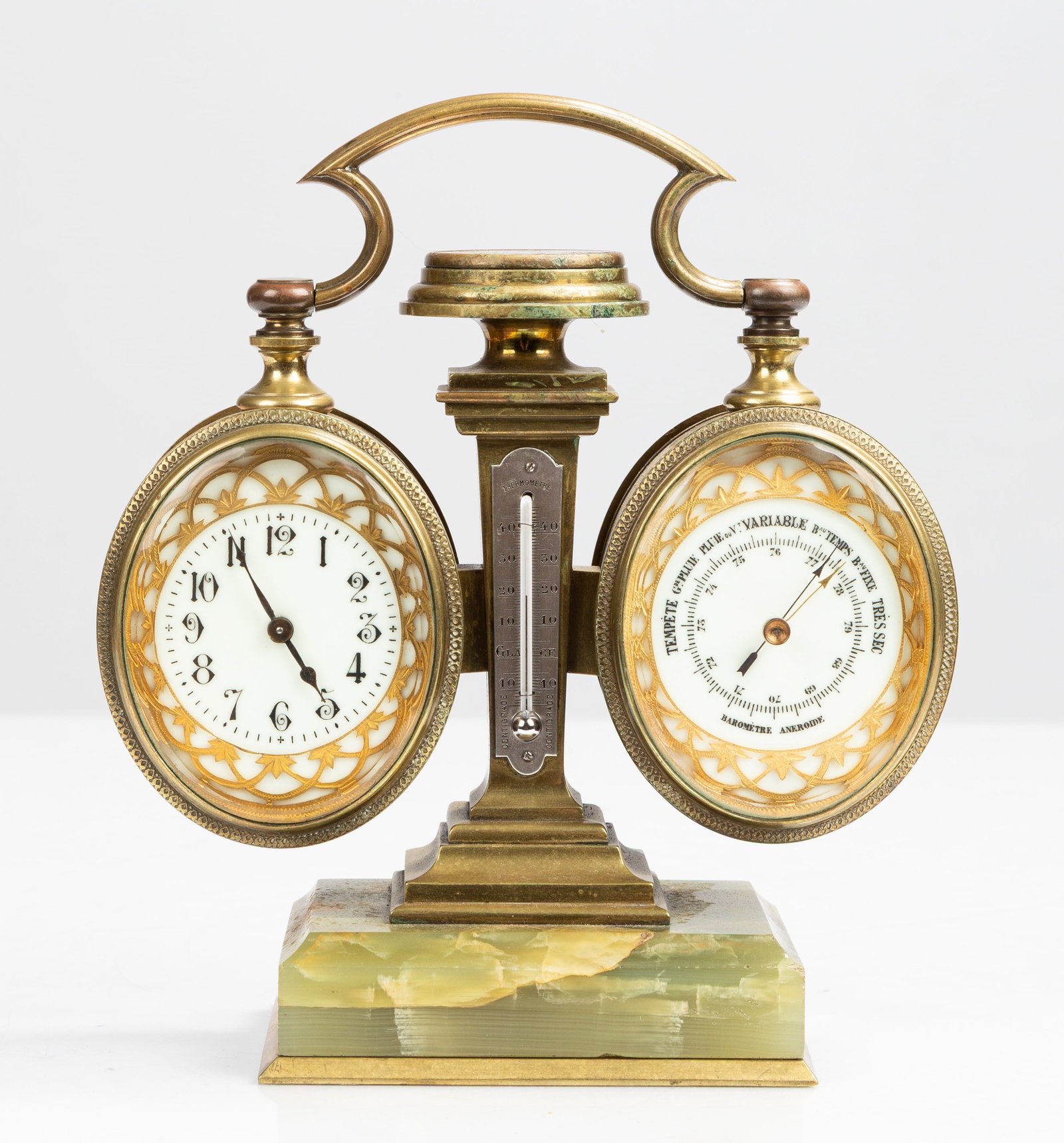 French Gilt Bronze and Onyx Desk Compendium: French Gilt Bronze and Onyx Desk Compendium Circa 1900. Timepiece and aneroid barometer in matching drum cases flanking a pillar with mercury thermometer, surmounted by a compass, on a green onyx base
