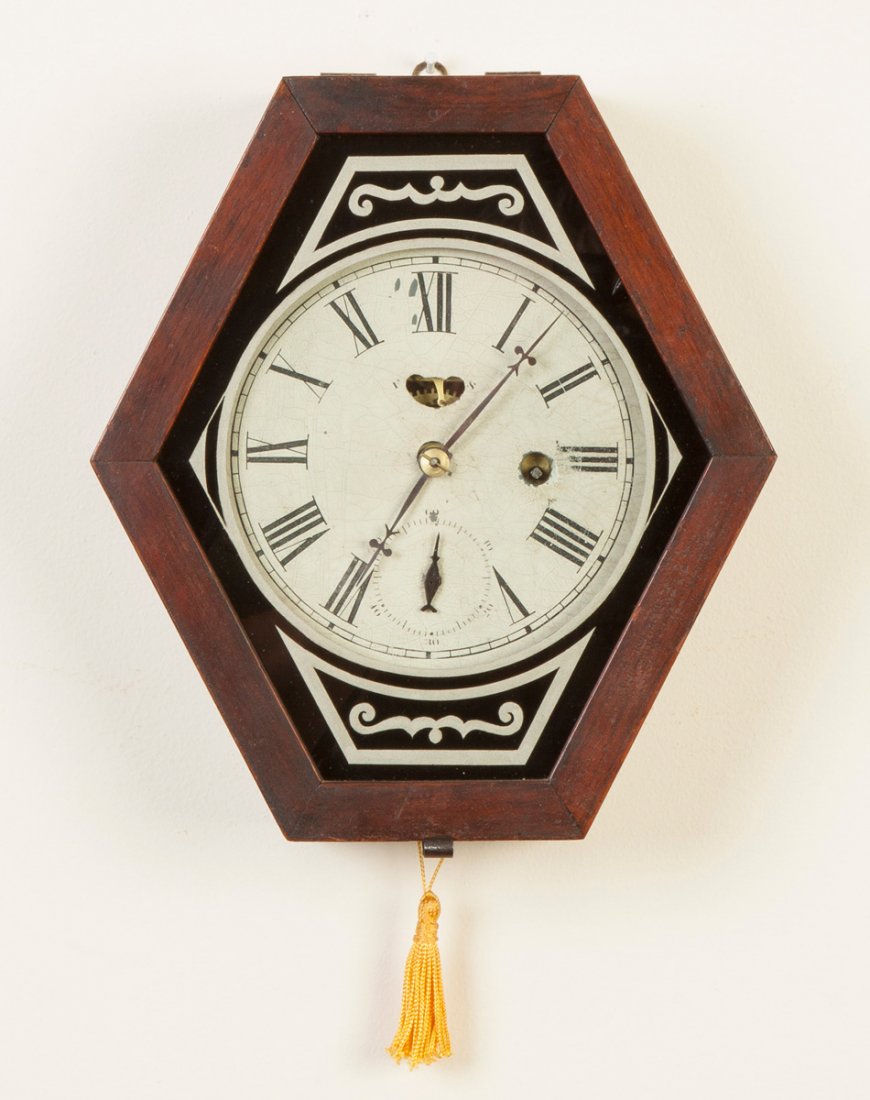 Waterbury Clock Co. Miniature Wall Clock: Waterbury Clock Co. Miniature Wall Clock. Hexagonal Walnut case, original finish. Original painted metal dial. Original reverse painted glass. Time only spring driven brass movement. Ht. 10". Ex. Vers