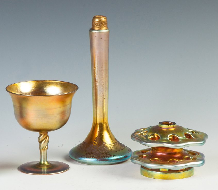 Three Steuben Gold Aurene Items: Three Steuben Gold Aurene Items. Goblet, #2361. Gold aurene, etched floral, missing atomizer. Gold Aurene flower frog, sgn. Carder. Ht. 7 1/2". Richard Bright and Kyle Goodman Collection, Corning, NY.