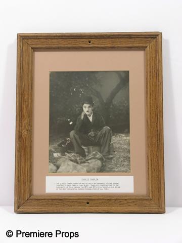 Charlie Chaplin Framed Photo: Charlie Chaplin wood framed movie photo of him sitting on a box thinking and brief description of his career at the bottom. (approx. 16 1/2" x 13 1/2")