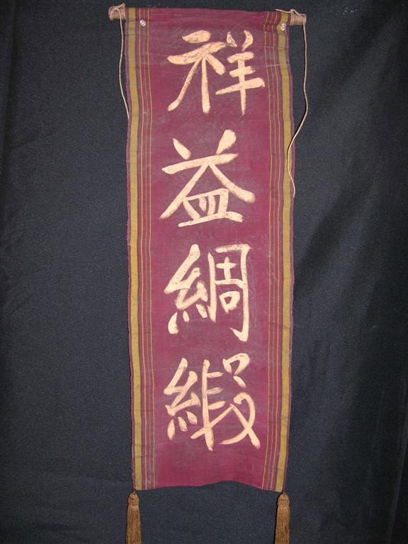 Pirates of the Caribbean: At World's End Banner: Screen used banner with painted Asian characters from Pirates of the Caribbean: At World's End. This red banner with gold lettering features tassels at its corners and is mounted to a wooden pole. (32