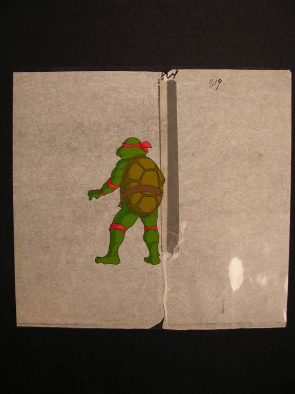 Teenage Mutant Ninja Turtle Cartoon Cel: Cartoon cel depicting Raphael the Ninja Turtle, drawn and painted for the 1980s animated series Teenage Mutant Ninja Turtles. Raphael, the turtle in red mask, is seen from the back in this cel. (11x10