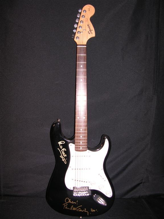 Paul McCartney and Peter Best Signed Guitar: Black and white electric Squire guitar signed by two members of the legendary Beatles, Paul McCartney and Pete Best. Both have signed in gold ink. McCartney has dated his signature 2001. Also included