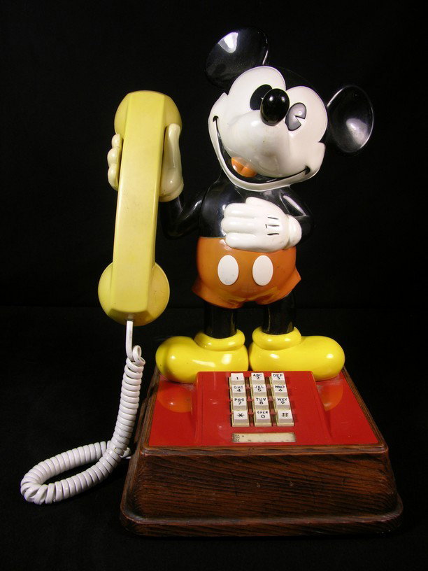 1970s Mickey Mouse Telephone: Vintage Mickey Mouse telephone from the 1970s, with Mickey holding the receiver and featuring a touch-tone number display on the red base.
