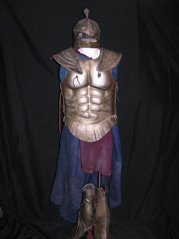 Immortals Hoplite Soldier Costume: From Tarsem Singh's 2011 action-blockbuster 'Immortals,' this is a custom made, screen worn Hoplite soldier stunt armor suit. The ensemble includes: a sleeveless red cloth tunic; highly detailed front