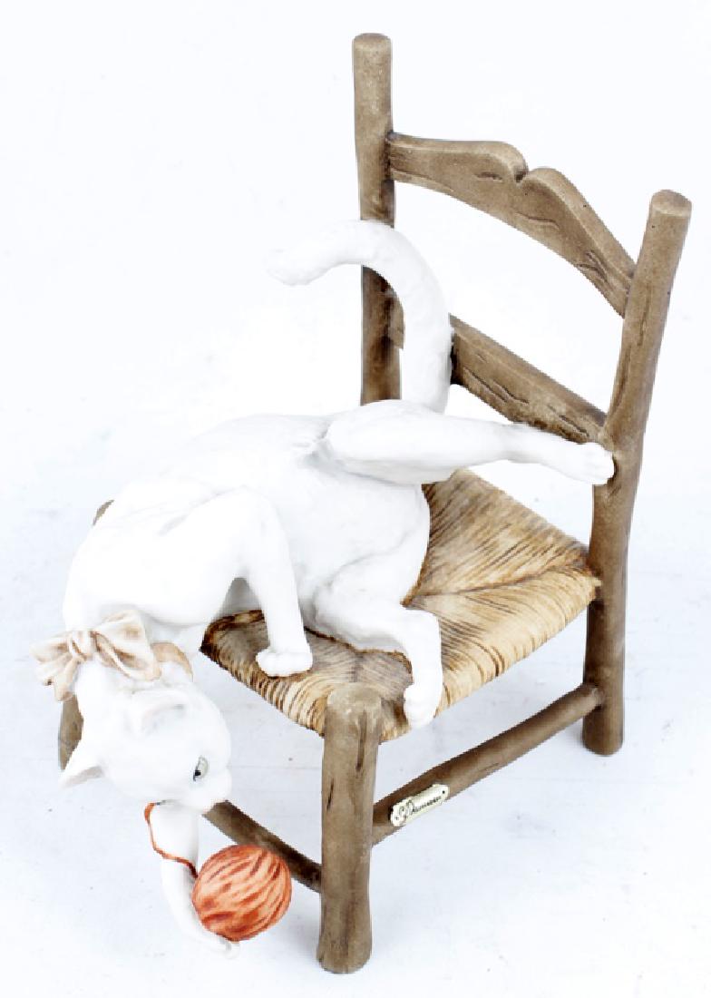 GIUSEPPE ARMANI PORCELAIN CAT ON CHAIR FIGURINE: GIUSEPPE ARMANI PORCELAIN CAT ON CHAIR FIGURINE Giuseppe Armani porcelain figurine titled "Cat on Chair". A white cat with a pink ribbon plays with a ball of yarn off of a wooden chair. Number 3166C, 