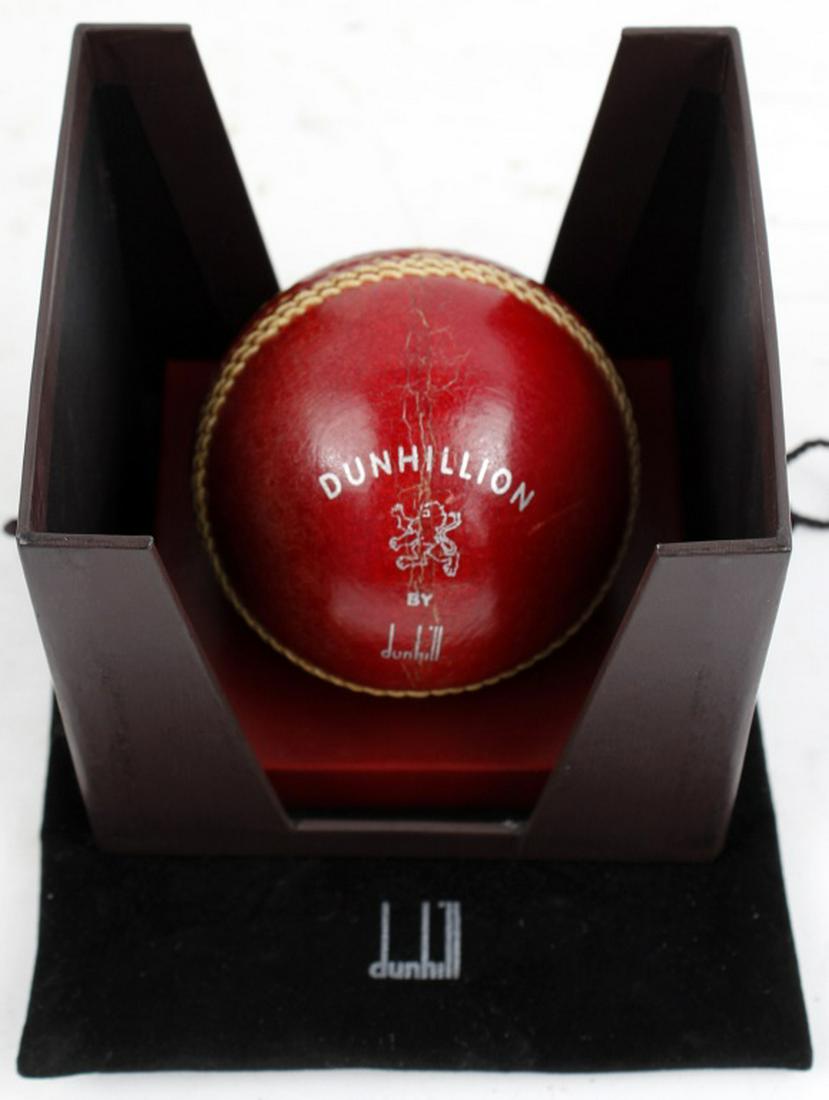 DUNHILL RED LEATHER CRICKET BALL DESK DISPLAY: DUNHILL RED LEATHER CRICKET BALL DESK DISPLAY A vintage Alfred Dunhill gentleman’s desk ornament in the form of a boxed cricket ball and weighted display stand bearing the “Dunhillion” Lion Logo