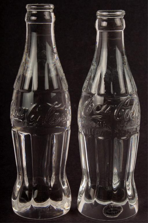 COCA-COLA LEAD CRYSTAL BOTTLES - LOT OF 2: COCA-COLA LEAD CRYSTAL BOTTLES - LOT OF 2 Coca-Cola lead crystal bottles - lot of 2. One plain replica bottle and one Centennial Coca-Cola bottle. Size: 7.75" Condition: Very fine