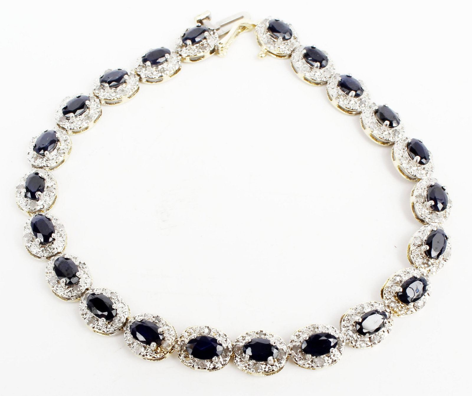 14K GOLD SAPPHIRE AND DIAMOND TENNIS BRACELET: 14k two tone gold sapphire and diamond tennis bracelet. (22) oval sapphires measuring 5mm x 3.5mm. Accented by (88) .01ct round diamonds. Weight: 9.5 grams Size: 7" Condition: Very Fine.