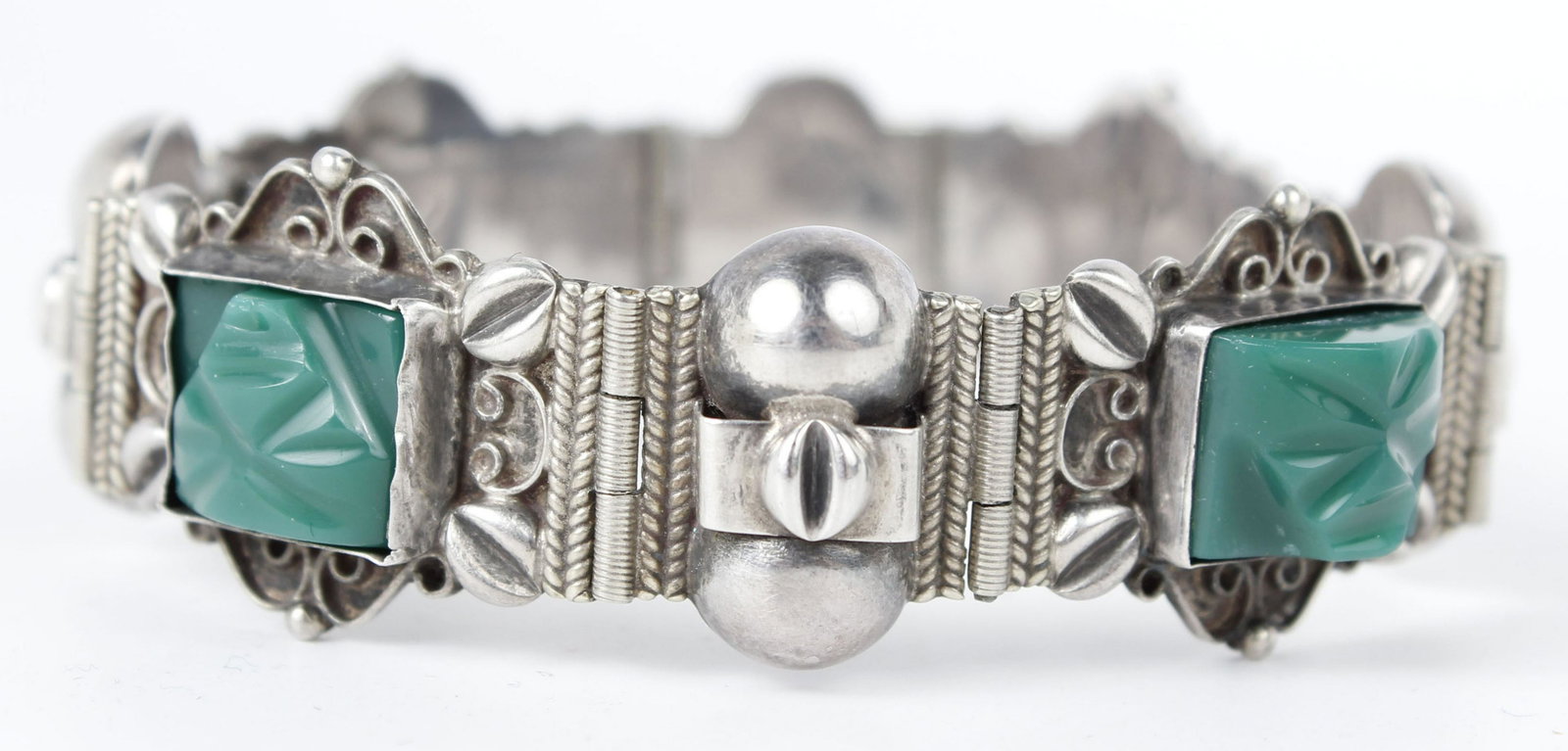 MEXICAN STERLING SILVER AZTEC BRACELET: Mexican sterling silver Aztec inspired bracelet with green stone face carvings. Measures 7.5" long Weight: 29.7 grams