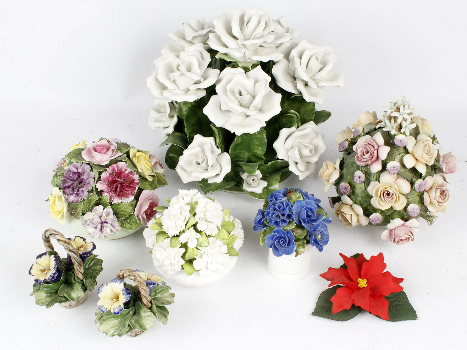 CAPODIMANTE & OTHER PORCELAIN FLORAL SPRAYS: 1 Capodimonte poinsettia & 2 blue flower baskets 1 Adderley Floral 1Coalport Floral 1Denton China1 Rose and floral display 1 Large white rose display Some pieces have small chips in petals Condition: