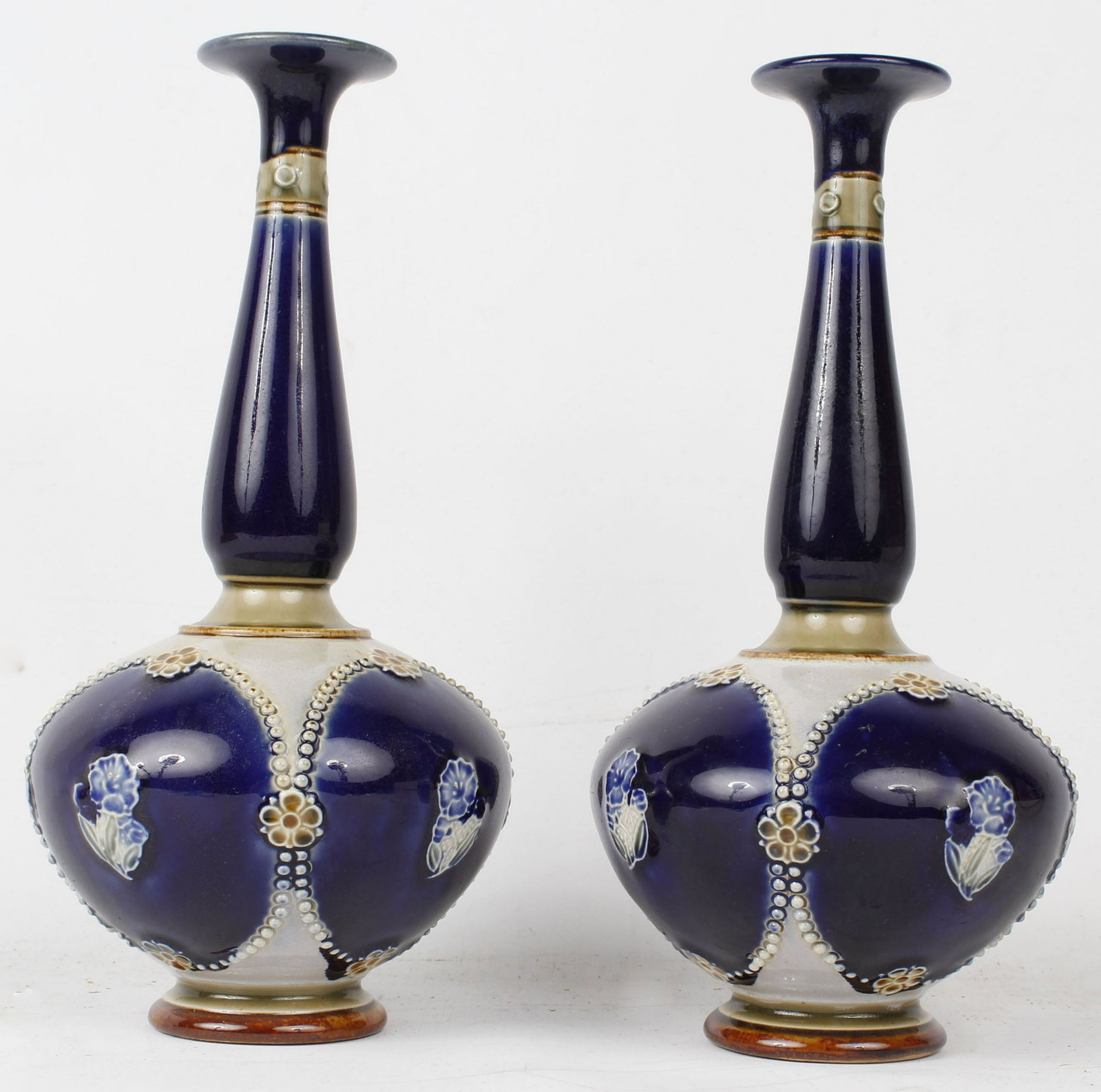 PAIR OF ROYAL DOLTON VASES ABBOTS / WEBB / AYLING: Royal Doulton #8365 white flowers and beading with accents of green and brown, Rich overall color a deep blue. Properly signed by the makers. Minnie Webb and Louisa Ayling with one countersigned by Ch