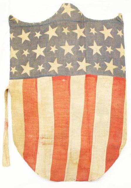 CIVIL WAR PERIOD FLAG IN THE FORM OF A SHIELD: CIVIL WAR PERIOD FLAG IN THE FORM OF A SHIELD Sewn canvas flag attached to a card shield. Size: 17" x 25" Condition: VGC EST. $200-500