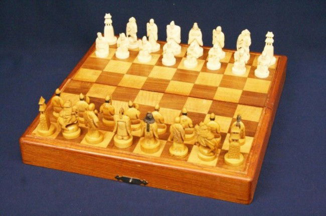 JAPANESE CARVED ELEPHANT IVORY CHESS SET: A good quality, hand carved elephant ivory chess set. The pieces stand approximately 2 inches. Complete with a wooden chess board/box. Paper label indicates that the set was made in Japan from genuine