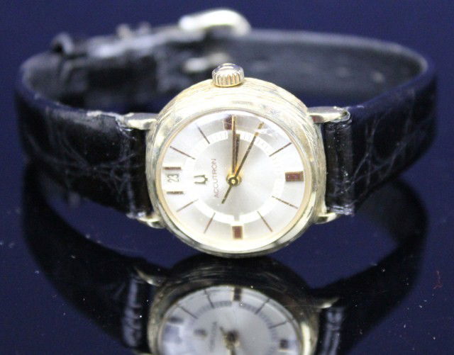 LADIES VINTAGE BULOVA ACCUTRON 14K GOLD WRISTWATCH: LADIES VINTAGE BULOVA ACCUTRON 14K GOLD WRISTWATCH Date of 1972. 14K yellow gold "tree bark" case. silver dial with gold roman numerals. Recessed date. Leather strap. Weight: 26g total Size: 20mm dial