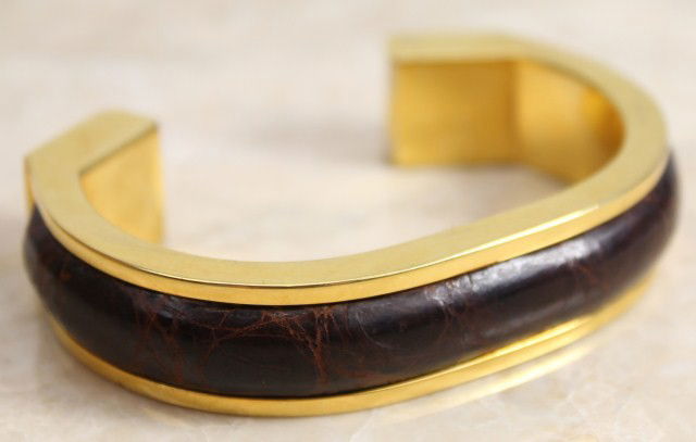 LADIES LOEWE LEATHER BANGLE BRACELET: A gold colored Loewe bangle bracelet with a leather strip fitted to the band. The diameter at the widest point is 2.5". Weight: 82 g Size: 2.5" diameter Condition: VGC