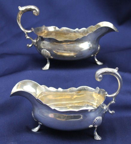 LOT OF TWO GEORGE III STERLING GRAVY BOATS: Two Georgian sterling silver sauce boats regarding the maker's mark of James Young. Crafted in the city of London and date marked for the year 1780. The two boats are matching and exhibit elegant curv