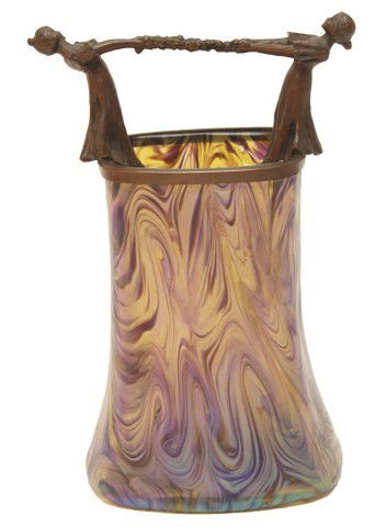 LOETZ IRIDESCENT GLASS VASE W/ ORNATE BRASS HANDLE: LOETZ IRIDESCENT GLASS VASE W/ ORNATE BRASS HANDLE A Loetz iridescent purple glass vase in the phenomenon pattern. Atop the vase is a decorative bronze casting of two young girls. A girl is on either
