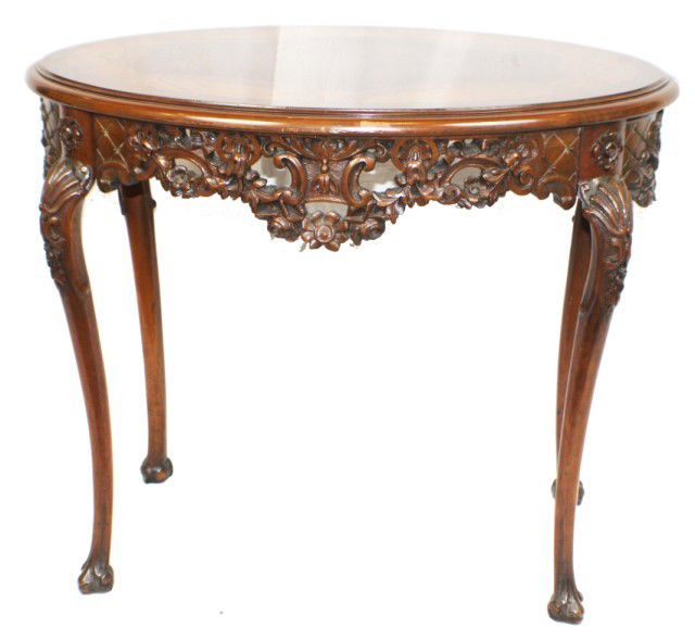 WOOD MARQUETRY COFFEE TABLE: WOOD MARQUETRY COFFEE TABLE Sizable coffee table with mixed wood circular marquetry. Table has intricate floral side carvings and elegant protruding legs set at 45 degree angles. Size: H: 31" W: 25" L