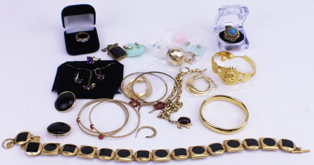 LOT OF GOLD COLORED COSTUME JEWELRY: LOT OF GOLD COLORED COSTUME JEWELRY 30 pieces of different costume jewelry, gold in color. Mixture of earrings, bracelets, pins, pendants, rings, and more. There are some sets of black stones and purp