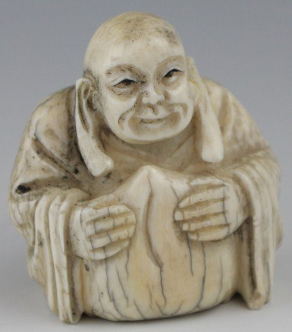 SIGNED ANTIQUE CARVED IVORY NETSUKE SEATED MAN: SIGNED ANTIQUE CARVED IVORY NETSUKE SEATED MAN Carved ivory netsuke of a robed, seated old man, with extraordinarily long ear lobes. Signed on bottom. Cracks and stain due to age. Size: 1.75"