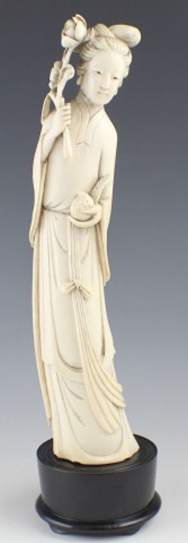 CARVED IVORY CHINESE LADY HOLDING FLOWERS & PEACH: CARVED IVORY CHINESE LADY HOLDING FLOWERS & PEACH A nicely executed carved ivory statue of a Chinese lady holding flowers and a peach. Sitting atop a wooden base. Size: 10" (excluding base)