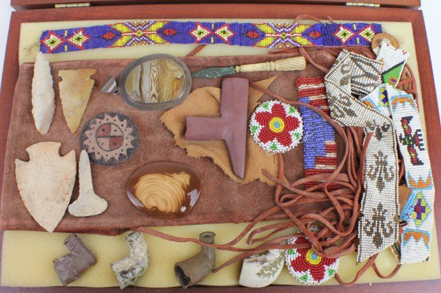 A DISPLAY OF NATIVE AMERICAN COLLECTIBLES: A DISPLAY OF NATIVE AMERICAN COLLECTIBLES A leather pouch with paint and bead work. Napped points (4). Pipe bowls. A metal arrowhead on a bone stem. Examples of beadwork of various design. Size: