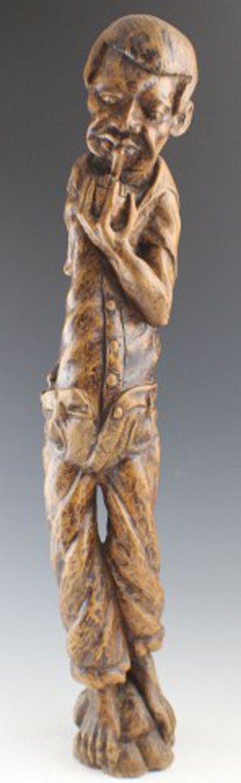 AMERICAN FOLK ART CARVED ROOT FIGURE: AMERICAN FOLK ART CARVED ROOT FIGURE Carved tree root, male figure with hands in pants, smoking pipe. American folk art. Signed on bottom "RL 40". Size: 22 1/2"