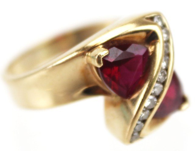 LADIES 10K YELLOW GOLD RUBY AND DIAMOND RING: LADIES 10K YELLOW GOLD RUBY AND DIAMOND RING Ladies, size 7 10K yellow gold ruby and diamond ring. Features two trillion cut rubies in figure eight pattern with 10 channel set round diamonds, approx 0