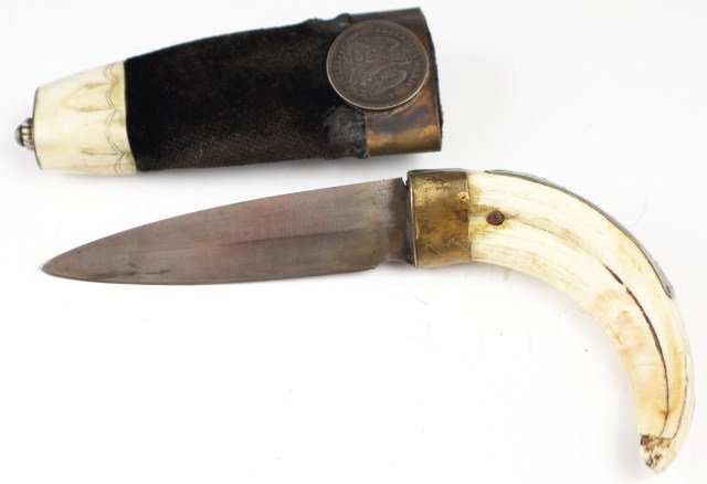 19TH CENTURY BOAR TUSK HANDLE BOOT KNIFE: 19TH CENTURY BOAR TUSK HANDLE BOOT KNIFE Blade of 3.5". Boar tusk grip (Some age wear). White metal plate with inscribed "Dios De La Muerte". Velvet covered sheath with bone chape. Applied 1879 silver