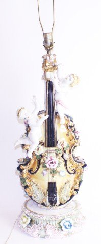 LARGE PORCELAIN VIOLIN AND CHERUB LAMP: LARGE PORCELAIN VIOLIN AND CHERUB LAMP Large hand painted violin and cherub lamp. Filled with floral designs and vibrant color. The lamp sits upon the original base. Some flowers have been chipped and
