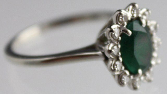 LADIES 18K WHITE GOLD EMERALD & DIAMOND RING: LADIES 18K WHITE GOLD EMERALD & DIAMOND RING Stunning 18K white gold ring featuring an oval cut deep green emerald surrounded by 12 round cut diamonds of approximately 0.01 ct each. Weight: 3.7g Size: