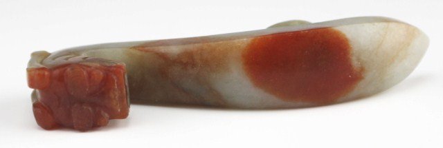 ANTIQUE CHINESE CARVED JADE BELT HOOK: ANTIQUE CHINESE CARVED JADE BELT HOOK Antique Chinese Carved Jade Belt Hook, modeled as a dragon, Jade with rust colored swirls. Hard Oval Button on rear. , Size: 3.25", Est. 150-300, Lot 30360